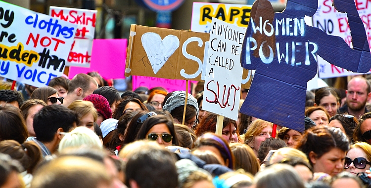 Group of women marching with banners about girl power and rape