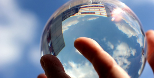 A hand holding a crystal ball, with reflections of a city